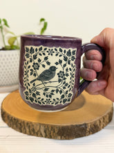 Load image into Gallery viewer, #008 - 16 oz. Purple mug with a bird and flower pattern. Unglazed clay where pattern is
