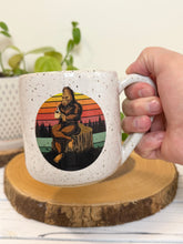 Load image into Gallery viewer, #007 - 16 oz. White speckled mug with Bigfoot drinking coffee
