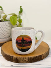 Load image into Gallery viewer, #009 - 18 oz. White speckled mug with Bigfoot in a canoe
