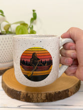 Load image into Gallery viewer, #009 - 18 oz. White speckled mug with Bigfoot in a canoe
