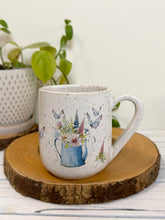 Load image into Gallery viewer, #028 - 14 oz. White speckled mug with watering can and flowers
