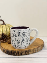 Load image into Gallery viewer, #005 - 14 oz. Skeleton patterned white speckled mug with dark purple inside
