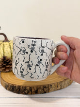 Load image into Gallery viewer, #005 - 14 oz. Skeleton patterned white speckled mug with dark purple inside
