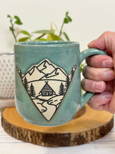 Load image into Gallery viewer, #022 - 16 oz. Mountain Cabin mug with green glaze (pattern on bare clay) and blue inside
