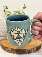 Load image into Gallery viewer, #022 - 16 oz. Mountain Cabin mug with green glaze (pattern on bare clay) and blue inside

