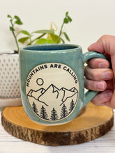 Load image into Gallery viewer, #023 - 16 oz. Mountains are calling mug with green glaze (pattern on bare clay) and blue inside
