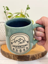 Load image into Gallery viewer, #024 - 16 oz. Adventure wilderness mug with green glaze (pattern on bare clay) and blue inside
